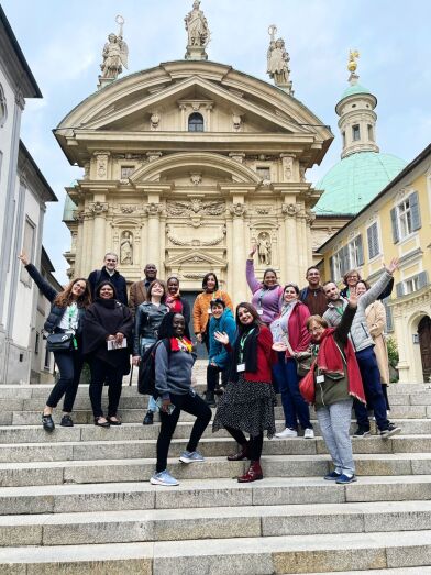 Group of participants standing on the steps in front of the mausoleum in Graz. They raise their hands in joy.