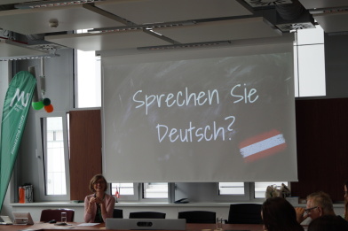 A teacher is teaching German and you see a screen with “Do you speak German?”.