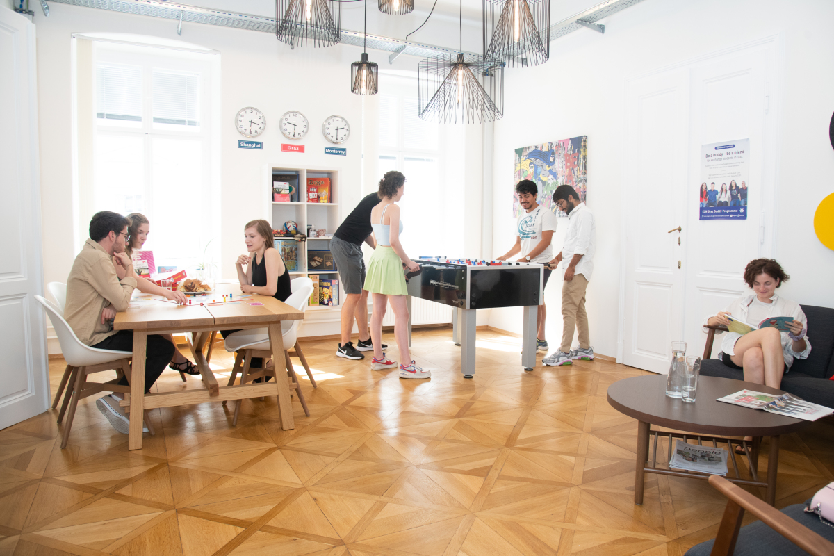 Eine Gruppe von Personen, die in der International Lounge Brettspiele und Tischfußball spielen und lesen 